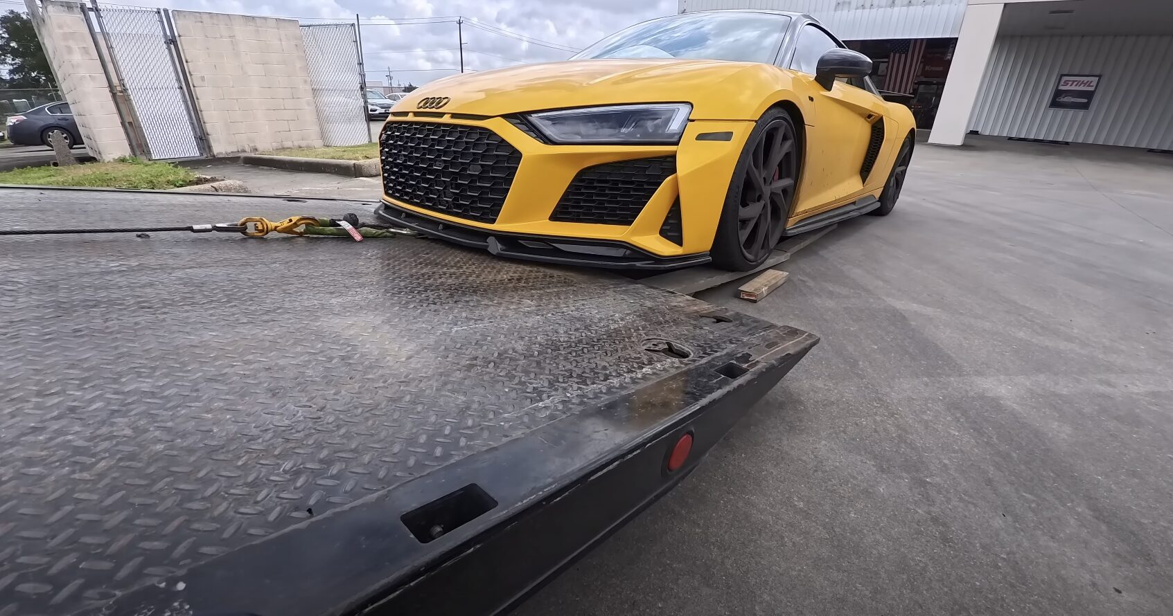 Professional flatbed tow truck with luxury vehicle safely loaded for transport